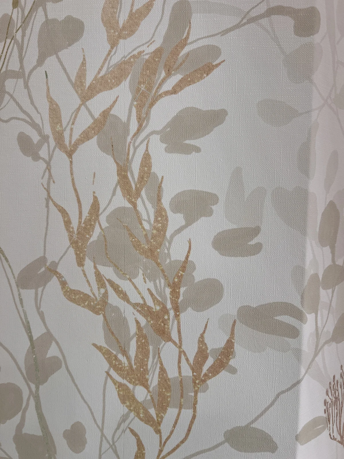 Close-up of soft gold and gray botanical wallpaper in a bathroom