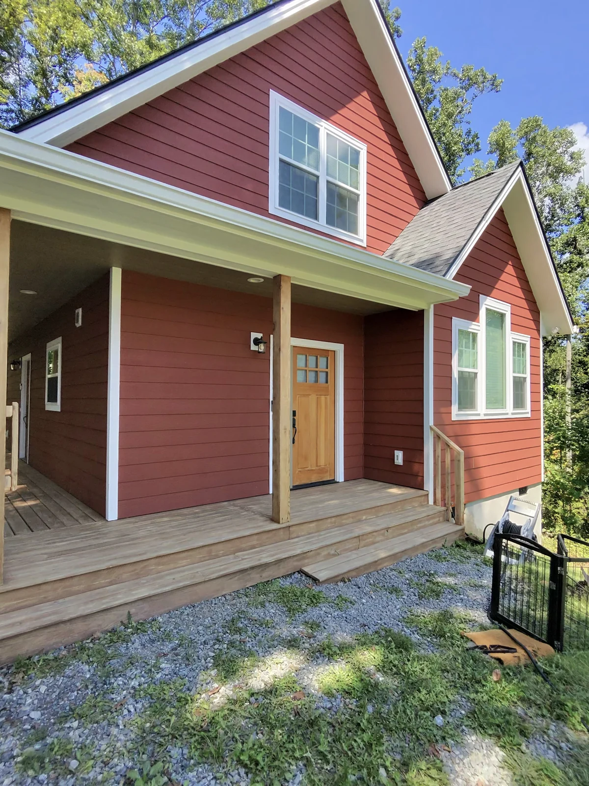 Bare wood deck and steps beside red siding before coating