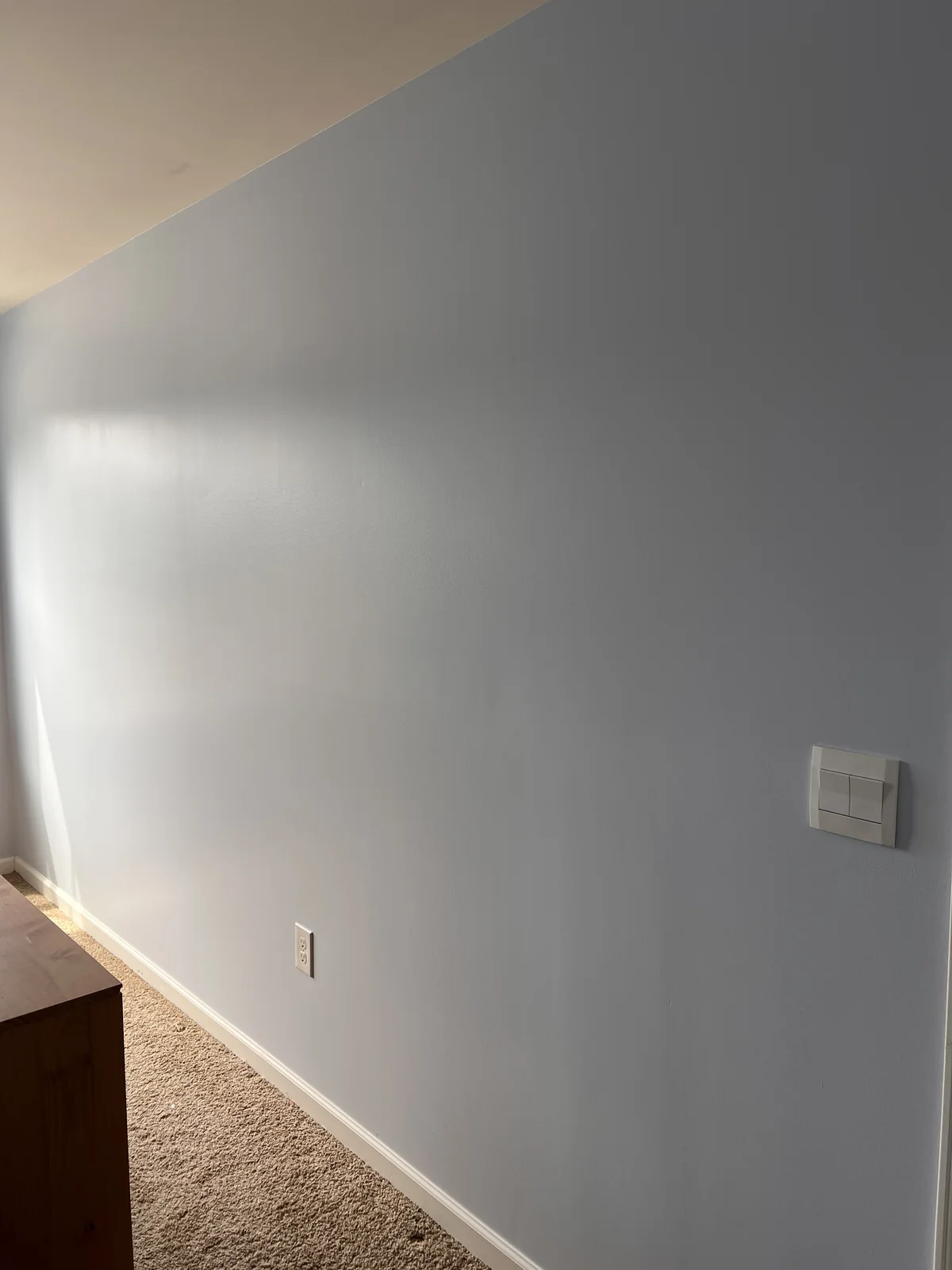 Pale blue painted wall with white baseboard and ceiling